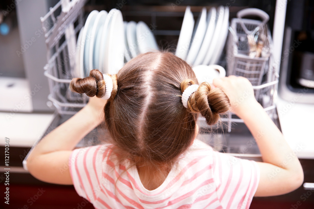 Fototapeta premium Little girl playing with dishwasher in kitchen