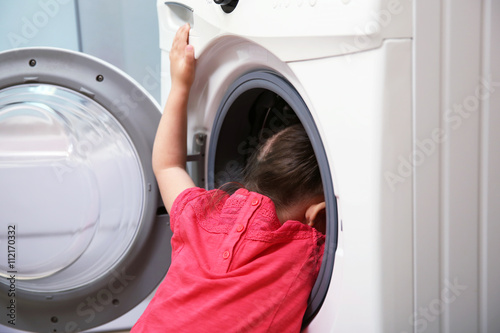 Little girl playing with washing machine