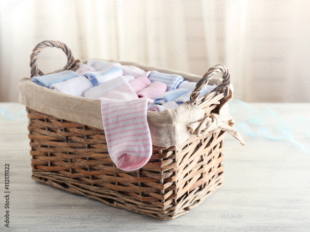 Obraz premium Baby socks in wicker box on wooden table