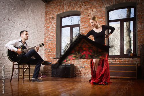 Young woman dancing flamenco and a man playing the guitar