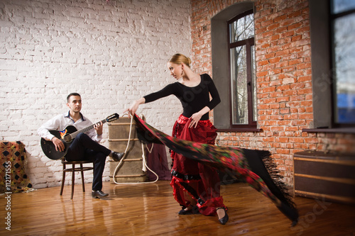 Young woman dancing flamenco and a man playing the guitar