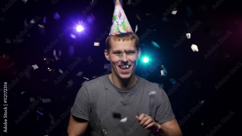 Guy throwing glitter confetti, blowing party whistle and dance. Close-up