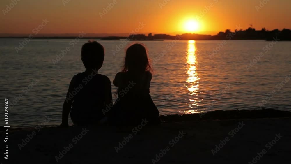 Boy and girl are watching the sunset over the sea Boy and girl are watching the sunset over the sea