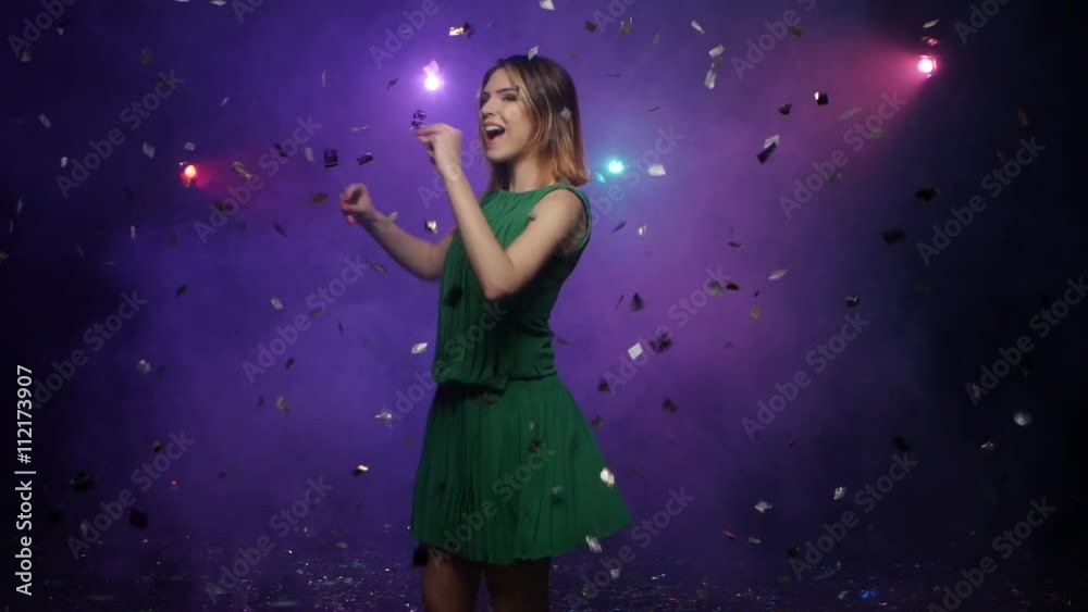 Dancing of young woman in green dress, under falling confetti Dancing of young woman in green dress, under falling confetti