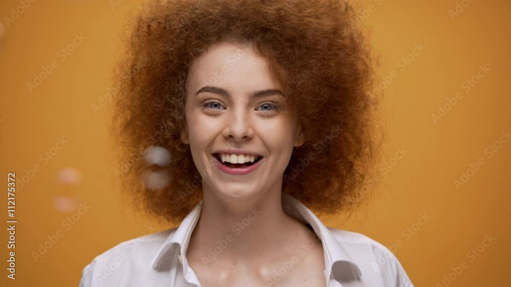 Funny fashion girl blowing soap bubbles on orange background. Close up. Funny fashion girl blowing soap bubbles on orange background. Close up.