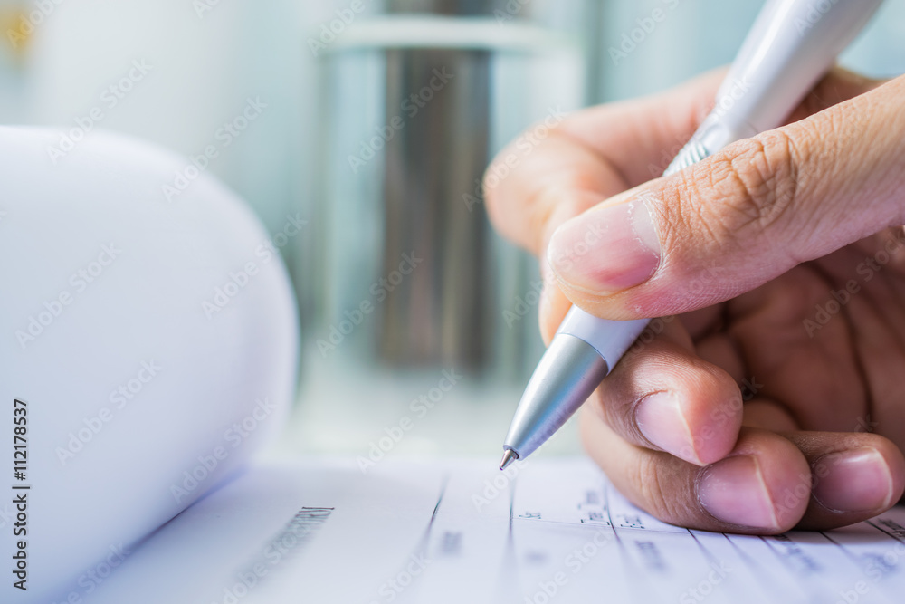Hand with pen over application form Hand with pen over application form