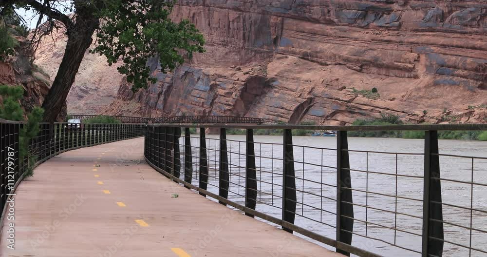 Moab Utah man walks along Colorado River trail. Southern desert. River shore walking bike path. Tourists come to nearby Arches and Canyonlands National Parks. Moab Utah man walks along Colorado River trail. Southern desert. River shore walking bike path. Tourists come to nearby Arches and Canyonlands National Parks.