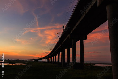 A train is crossing bridge at  Pa Sak Jolasid Dam, Thailand in sunset time photo