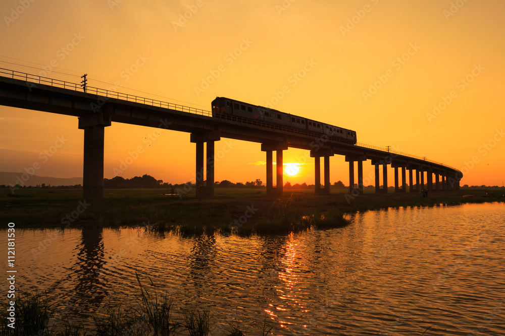 A train is crossing bridge at Pa Sak Jolasid Dam, Thailand in sunset time A train is crossing bridge at Pa Sak Jolasid Dam, Thailand in sunset time