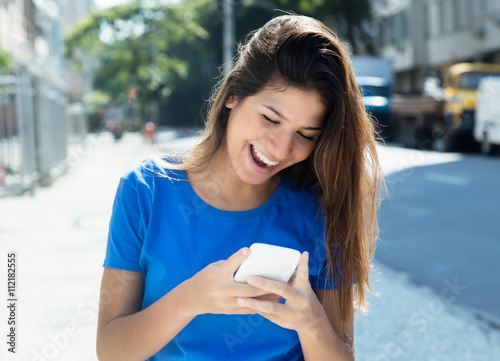 Frau im blauen Shirt surft mit Handy photo