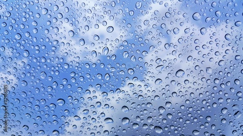 Raindrops on glass and blurred sky background