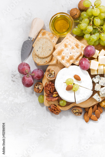 camembert, grapes and snacks on a white background, vertical