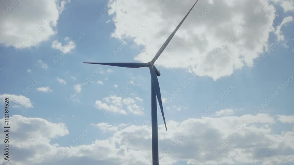 Aerial view: Single wind turbine power with sky cloudly background and road with traffic Aerial view: Single wind turbine power with sky cloudly background and road with traffic