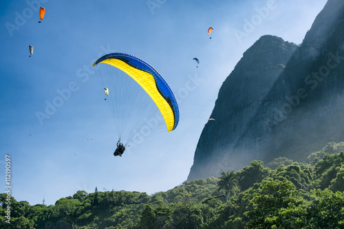 Paraglider passes along the misty greenery of Pedra da Gavea Mountain on its way to land at São Conrado Beach in Rio de Janeiro, Brazil