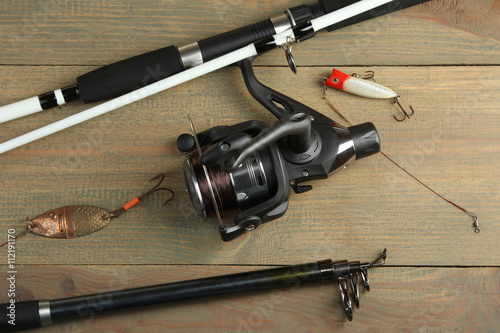 new spinning reel with a bait and hook on a brown wooden background
