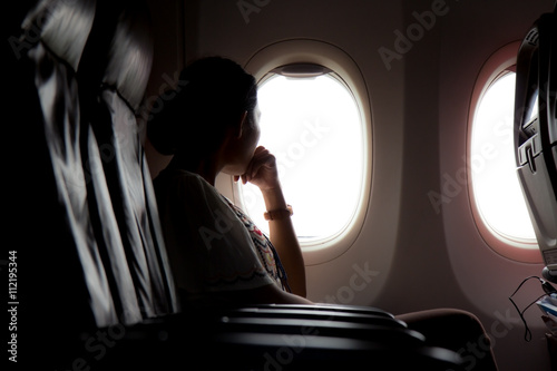 woman looks out the window of an airplane