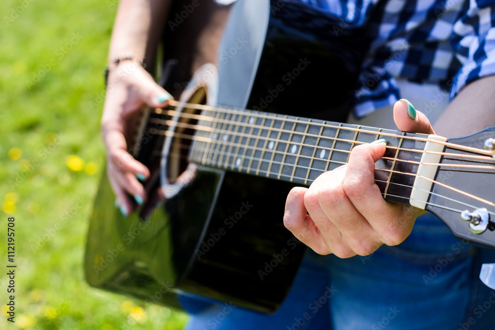 girl on a green meadow playing guitar