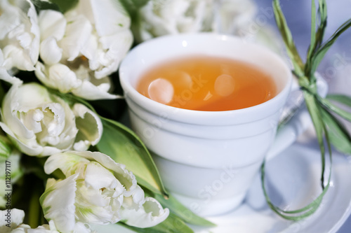 Чай в белой чашке и букет тюльпанов