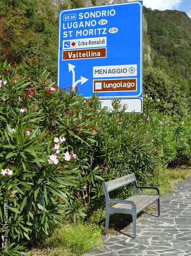 Wooden bench in Cadenabbia, on the shore of Lake Como, frontlake (lungolago) and beatiful oleander in flower. Italy, september 2015 photo