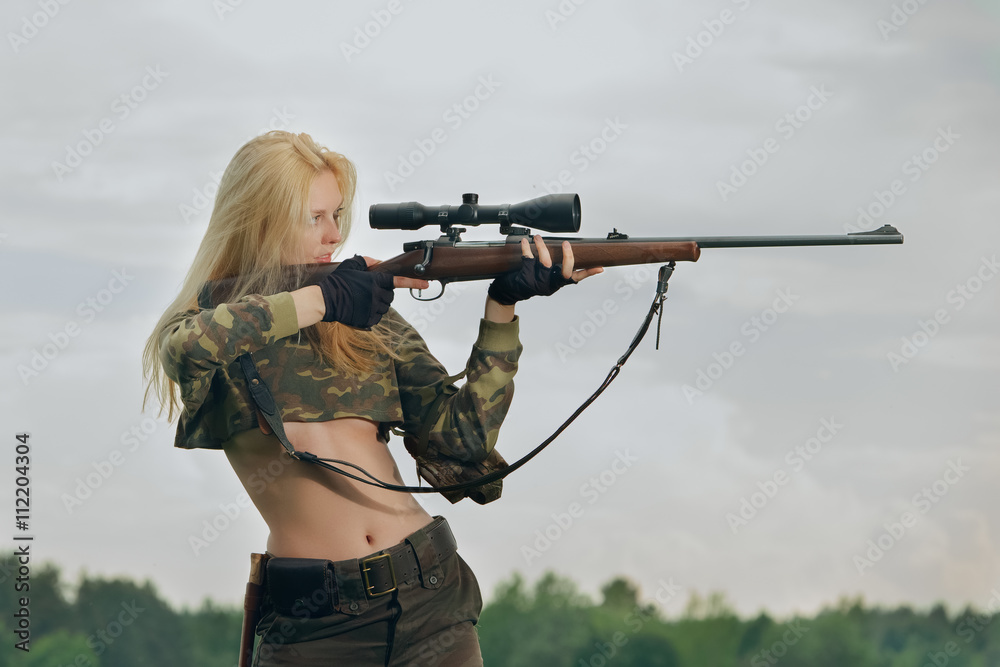 Pretty hunter girl aiming with hunting rifle in the outer wood. Stock ...