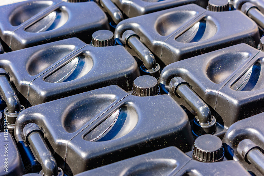 Topside of black plastic oil canisters on a pallet. Topside of black plastic oil canisters on a pallet.