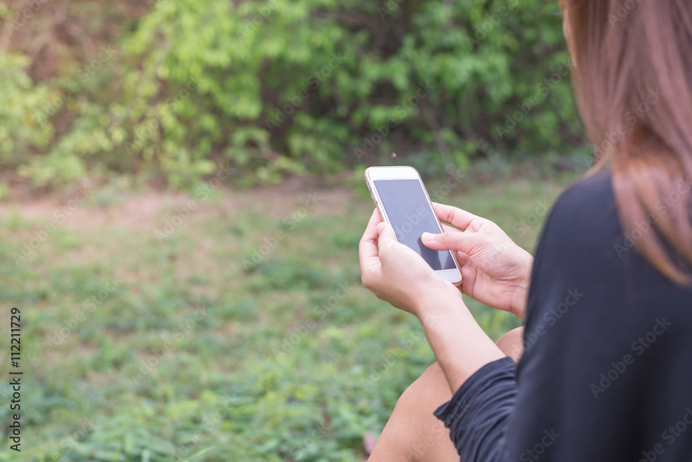 Asian woman with smartphone outdoors in park. Closeup of female hand