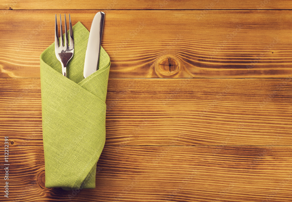 knife and fork at napkin on wood