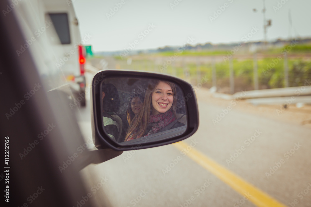 Women looking at the camera through the car side view mirror Women looking at the camera through the car side view mirror
