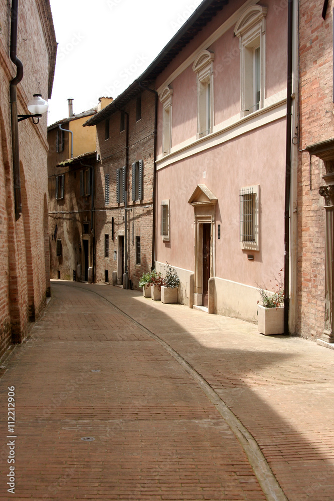 Lane in Urbino, with small street and little buildings of red bricks, Italy