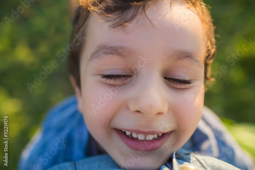 Portrait of a smilling cute little boy wiht closed eyes (tilt view)