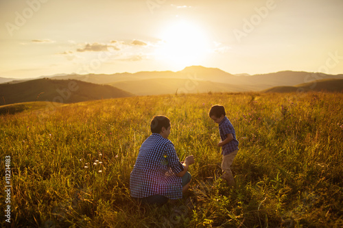 Father and son play on a field at the sunset