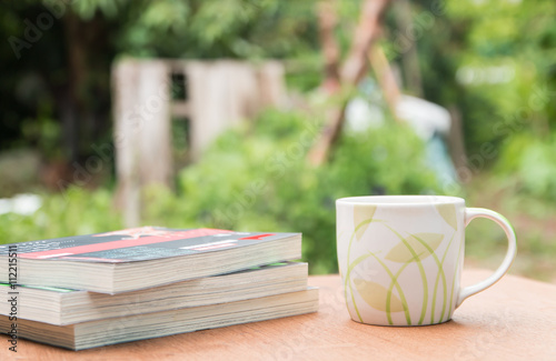 a cup of coffee and books on the wooden table