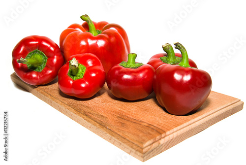 Several  peppers on a wooden cutting board.