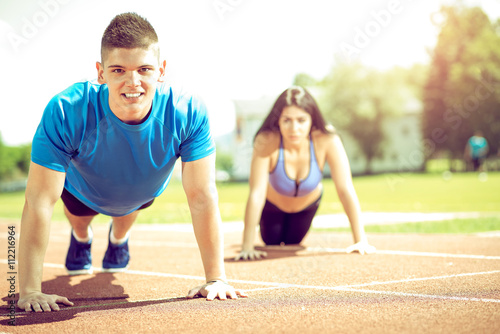 Young couple doing push ups on track.