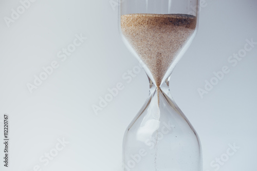 Sand flowing through an hourglass concept for time running out, background