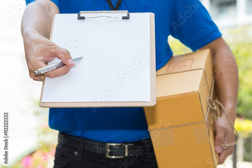 Delivery Man holding parcel and giving pen to client © comzeal