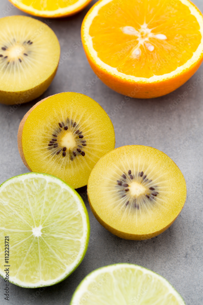Mixed citrus fruit lemons, orange, kiwi, limes on a gray backgro Mixed citrus fruit lemons, orange, kiwi, limes on a gray backgro