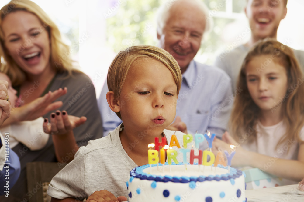 Boy Blows Out Birthday Cake Candles At Family Party Boy Blows Out Birthday Cake Candles At Family Party