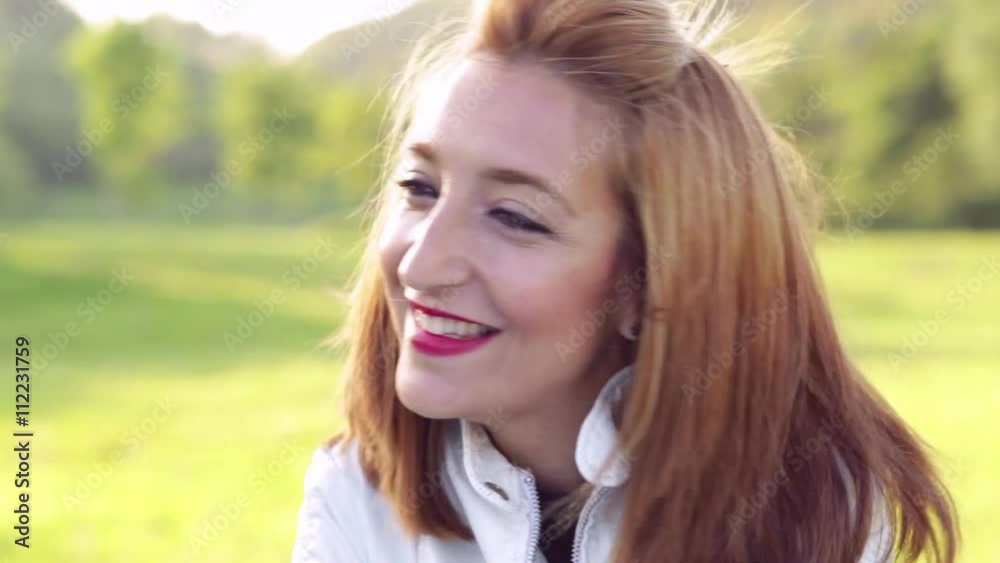 Woman outdoors in a park, looking at camera, very happy, winking an eye. Woman outdoors in a park, looking at camera, very happy, winking an eye.