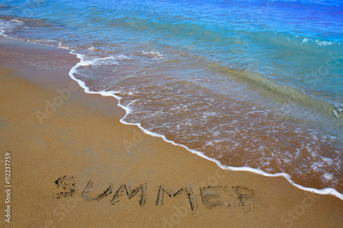 Summer spell written word in sand of a beach