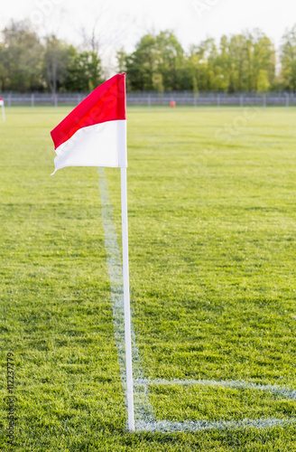 Eine rotwei  e Eckfahne steht in der Ecke eines Fu  balltrainingsplatzes. Das   ben einer Standardsituation steht auf dem Plan