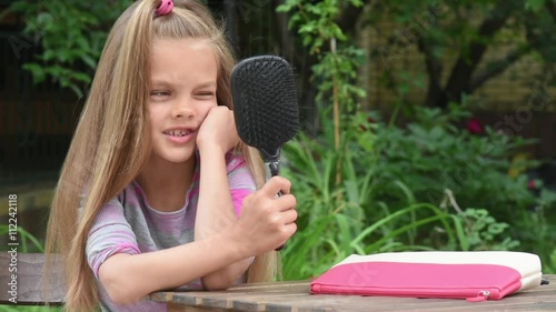 The girl sees himself in a mirror built into the comb and hamming photo