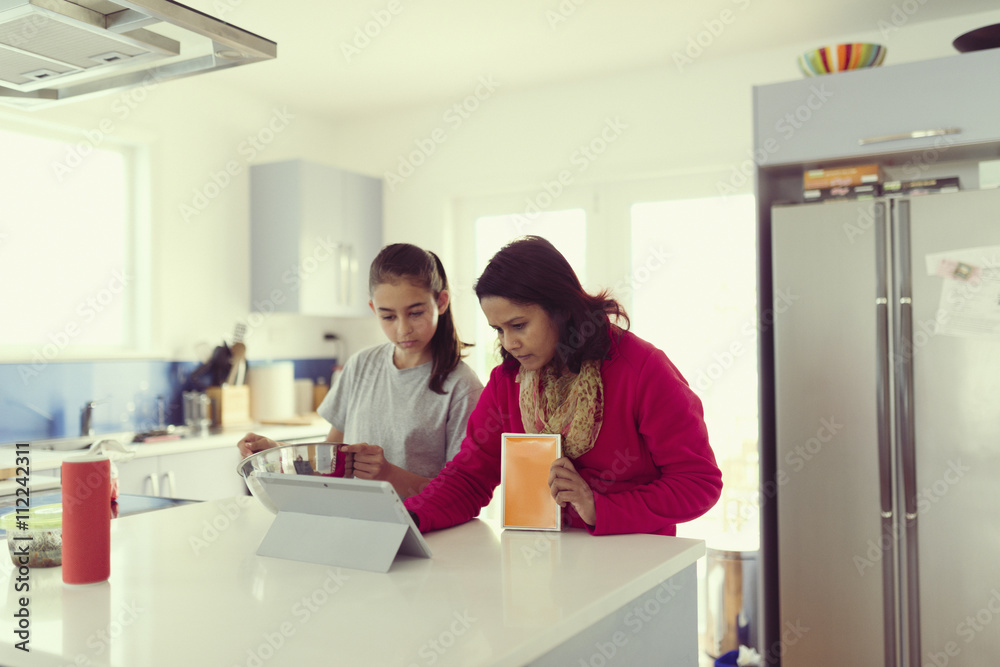 Mother and daughter using digital tablet in kitchen Mother and daughter using digital tablet in kitchen