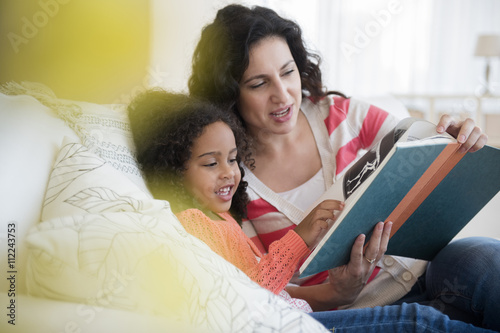 Mother and daughter reading on sofa