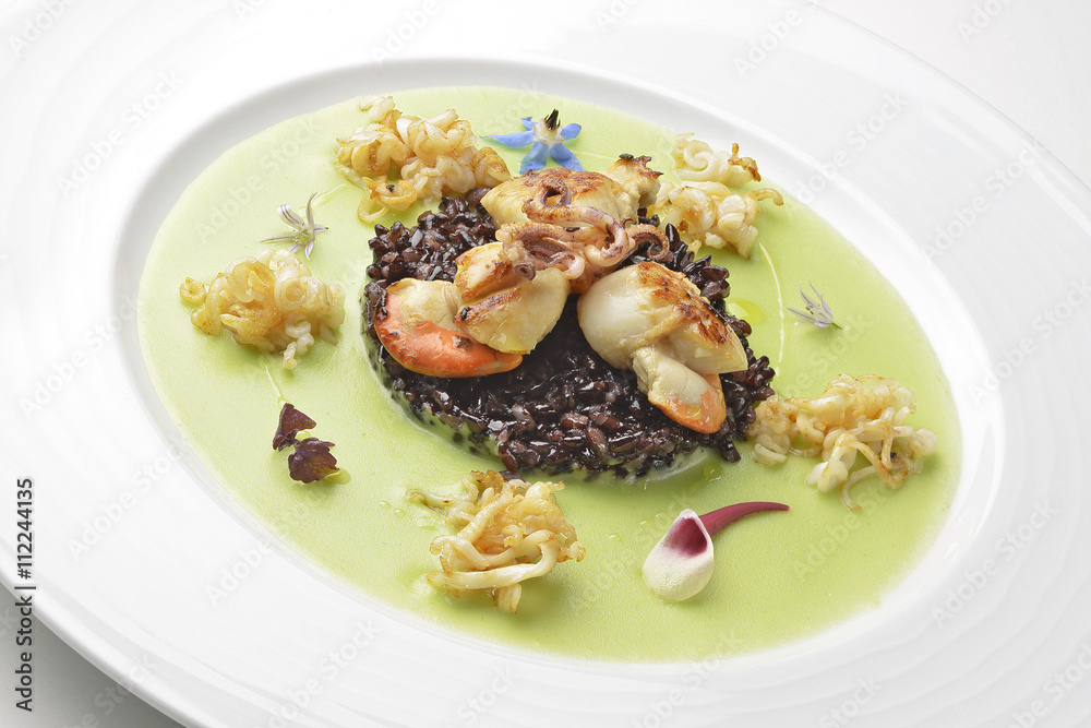 Appetizer braised scallops and black rice on pea cream