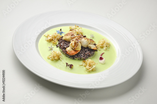 Appetizer braised scallops and black rice on pea cream