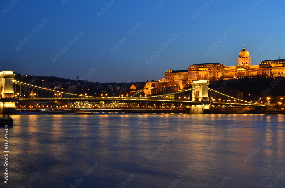 Naklejka premium Budapest Royal Castle and Szechenyi Chain Bridge at dusk time from Danube river, Hungary.