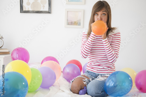 Mixed race woman blowing up balloons photo