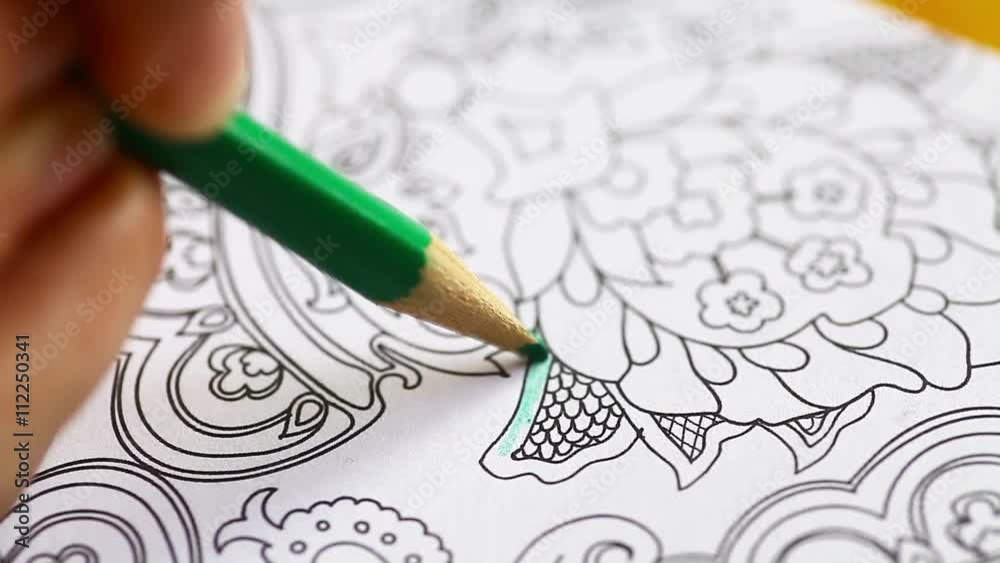 Color video of a hand holding a pencil and coloring an adult coloring book.