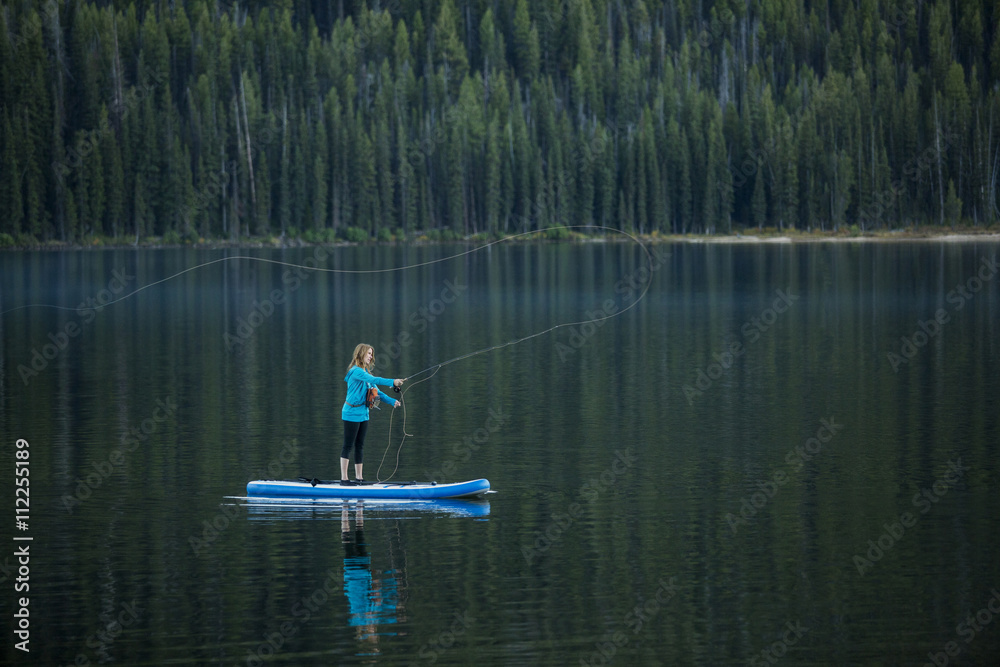 Caucasian woman fishing from paddle board in river Caucasian woman fishing from paddle board in river